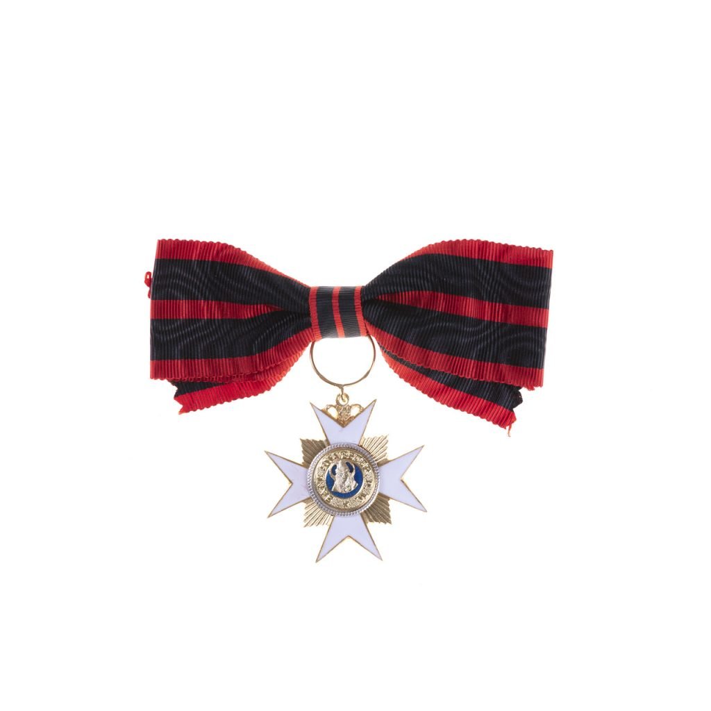 Un fiocco a righe nere e rosse con una medaglia a forma di stella in oro e bianco, ispirata alla classica Decorazione per Dama Ordine San Silvestro Papa.