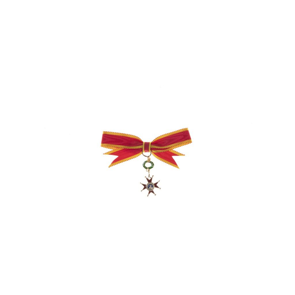 La Miniatura per Dama Ordine San Gregorio Magno presenta un fiocco di nastro rosso e giallo con una piccola medaglia a forma di stella, su sfondo bianco.