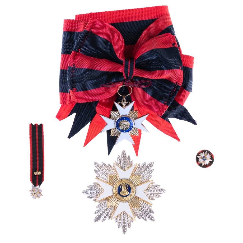 Fascia a righe rosse e blu con medaglie, distintivo a forma di stella e spilla a nastro abbinata, rappresentante la Decorazione per Cavaliere Gran Croce Ordine San Silvestro Papa.