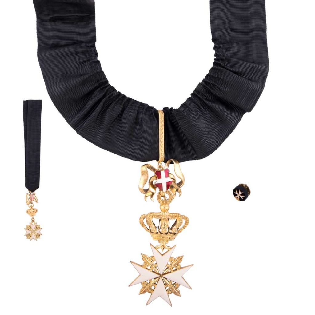 Medaglia con croce di Malta bianca e oro, corona, su nastro nero con due piccoli oggetti correlati. Prodotto: Decorazione per Cavaliere Grazia Magistrale S.M.O.M.