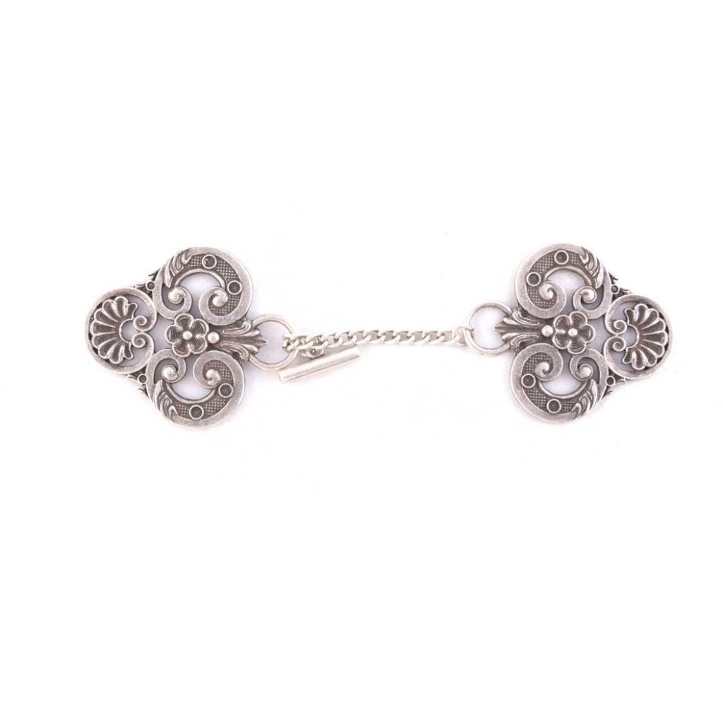 Spilla "Ganci per Piviale Conchiglia" in argento decorato, con due piastre incise a fiori collegate da una corta catena, ispirata al raffinato stile dei ganci piviali Gammarelli.