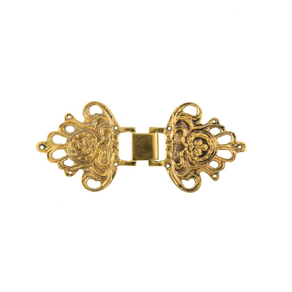 Il Ganci per Piviale Modello Giglio Antico è un fermaglio d'oro ornato da intricati dettagli floreali e a volute, raffigurato isolato su sfondo bianco.