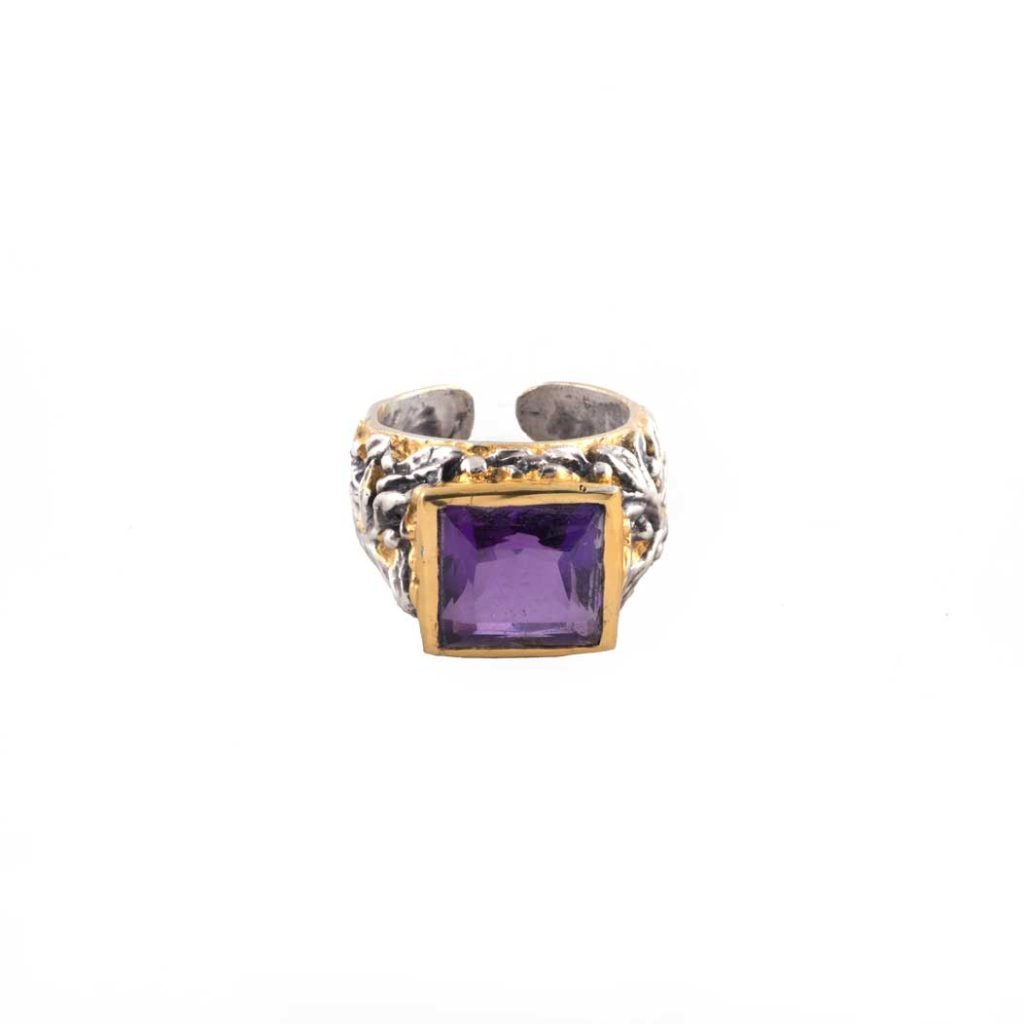 Anello con Ametista e Ulivo Cesellato: un anello in argento con fascia ornata e grande gemma quadrata viola incastonata in un castone d'oro, che spicca su uno sfondo bianco.