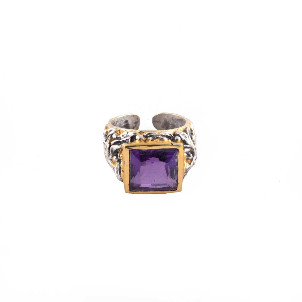 Anello con Ametista e Ulivo Cesellato: un anello in argento con fascia ornata e grande gemma quadrata viola incastonata in un castone d'oro, che spicca su uno sfondo bianco.