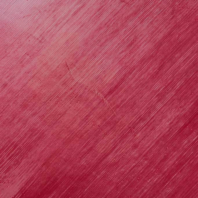 Primo piano della superficie rossa di Lama, caratterizzata da linee diagonali e sottili graffi.