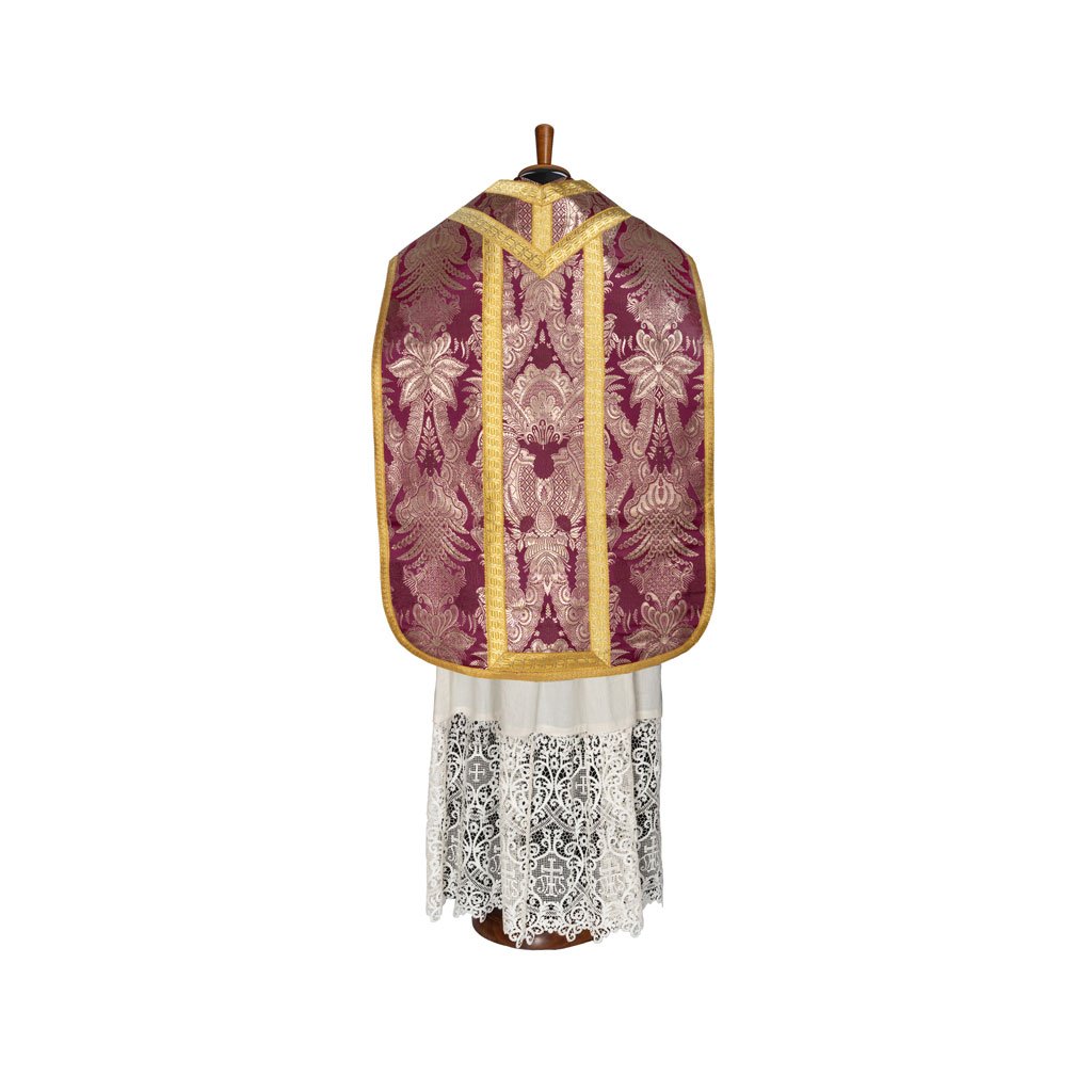 La Pianeta Romana Lampasso GAM1 Misto Oro di Gammarelli Sartoria, nei colori viola e oro, è esposta su una vestaglia di pizzo bianco su un manichino di legno su sfondo bianco.