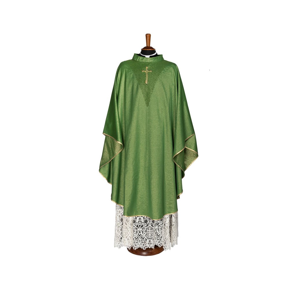 La Casula Gotica con V Lavorata, una casula gotica verde con croce d'oro, è esposta su un supporto sopra un albo di pizzo su sfondo bianco.