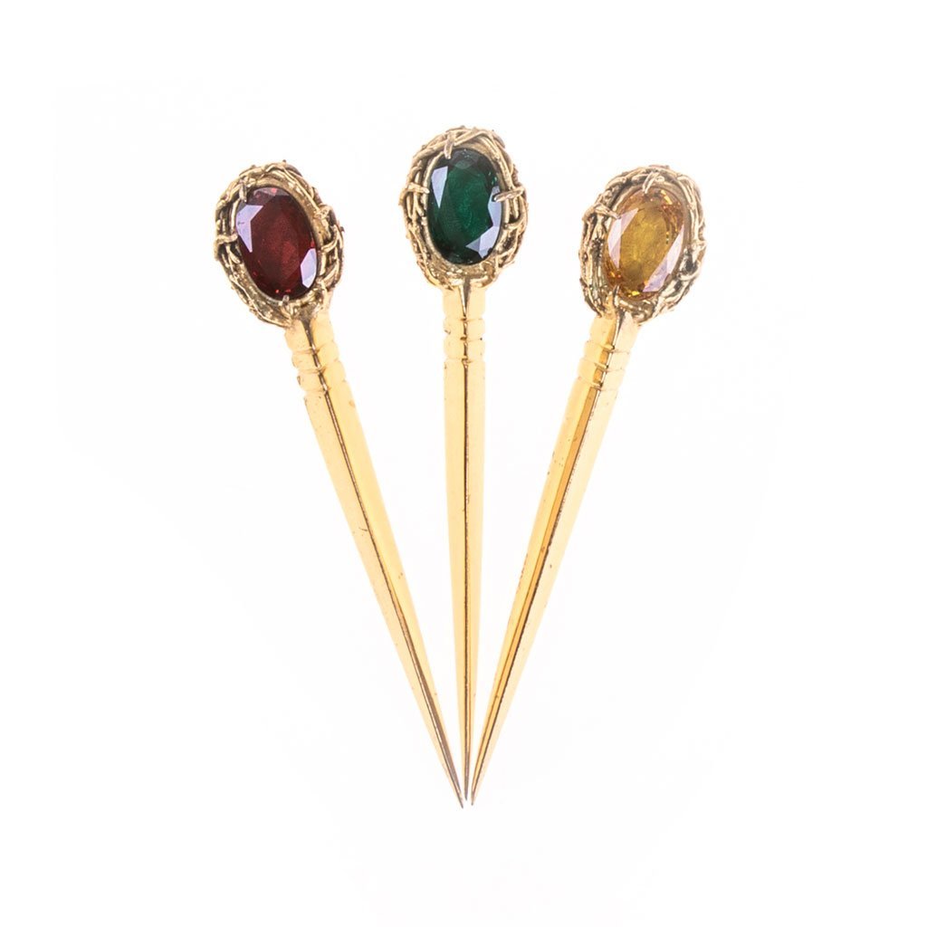 L'Acicule con Corona di Spine presenta tre spille ornate con base in oro, ciascuna sormontata da una gemma distinta in rosso, verde e giallo.